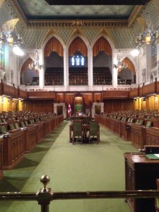 The House of Lords chamber in the Parliament Building.  The color green is dominant. The Senate has a similar chamber, where the color red is dominant