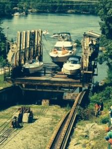 Notice that the larger boat is suspended from cables. Smaller boats sit in cradles built into the carriage. The Joint Adventure, since it has two hulls, sits directly on the wooden deck of the carriage. Notice that everyone stays on the boat and rides with it as it transits the marine railway