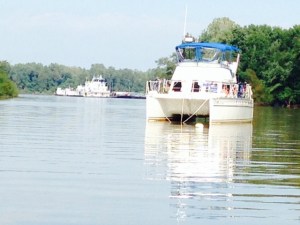 Another image of the Joint Adventure at anchor, taken from the dinghy.  Notice the tug pushing its barges in the background, heading up the Mississippi