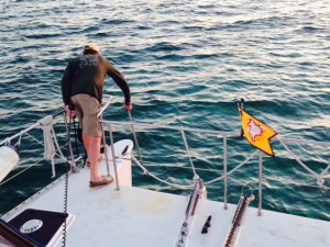 In the Bahamas, we always used a trip line with a float on the anchor so we could pull it up if it got snagged on a rock or coral or other obstruction on the seabed. Here Jim is pulling up the float on the trip line while the anchor is being raised.